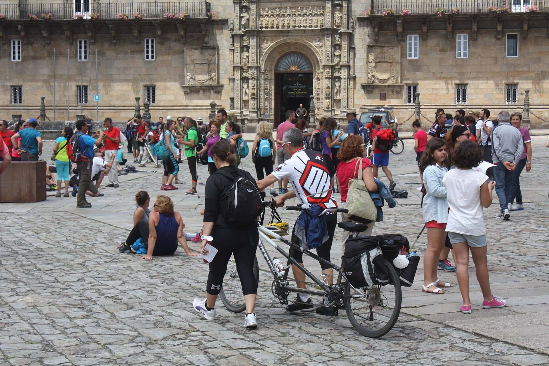 Peregrinos con mochilas descansando en la Praza do Obradoiro frente a la Catedral