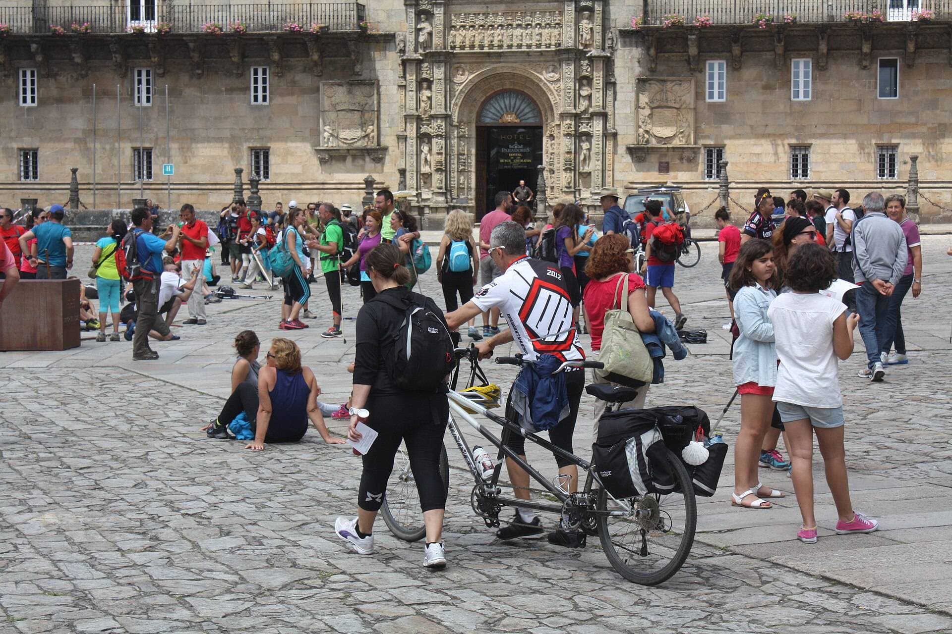 Peregrinos con mochilas descansando en la Praza do Obradoiro frente a la Catedral