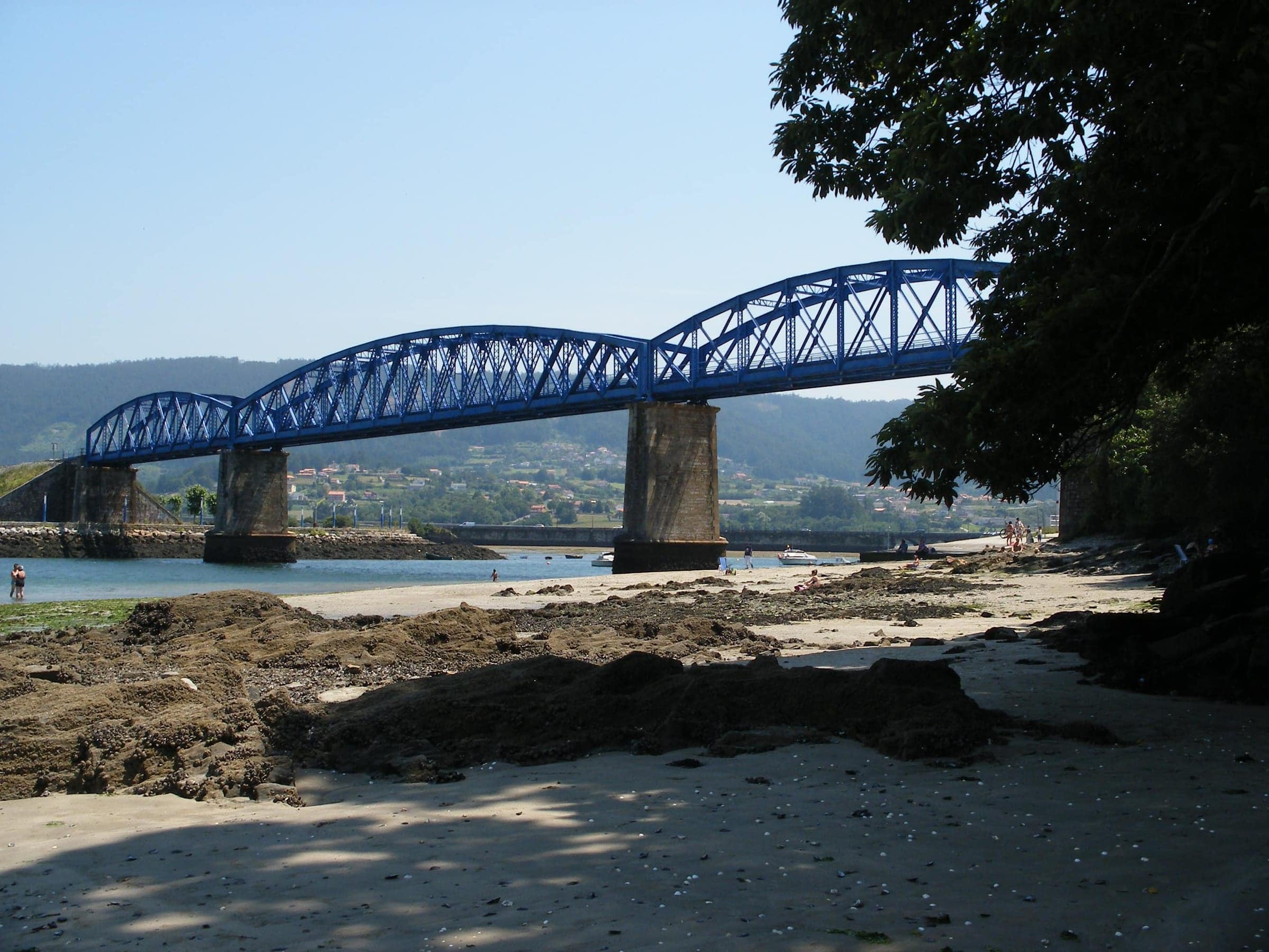Puente de hierro azul del ferrocarril sobre la ría del Eume en Pontedeume, visto desde la playa a marea baja